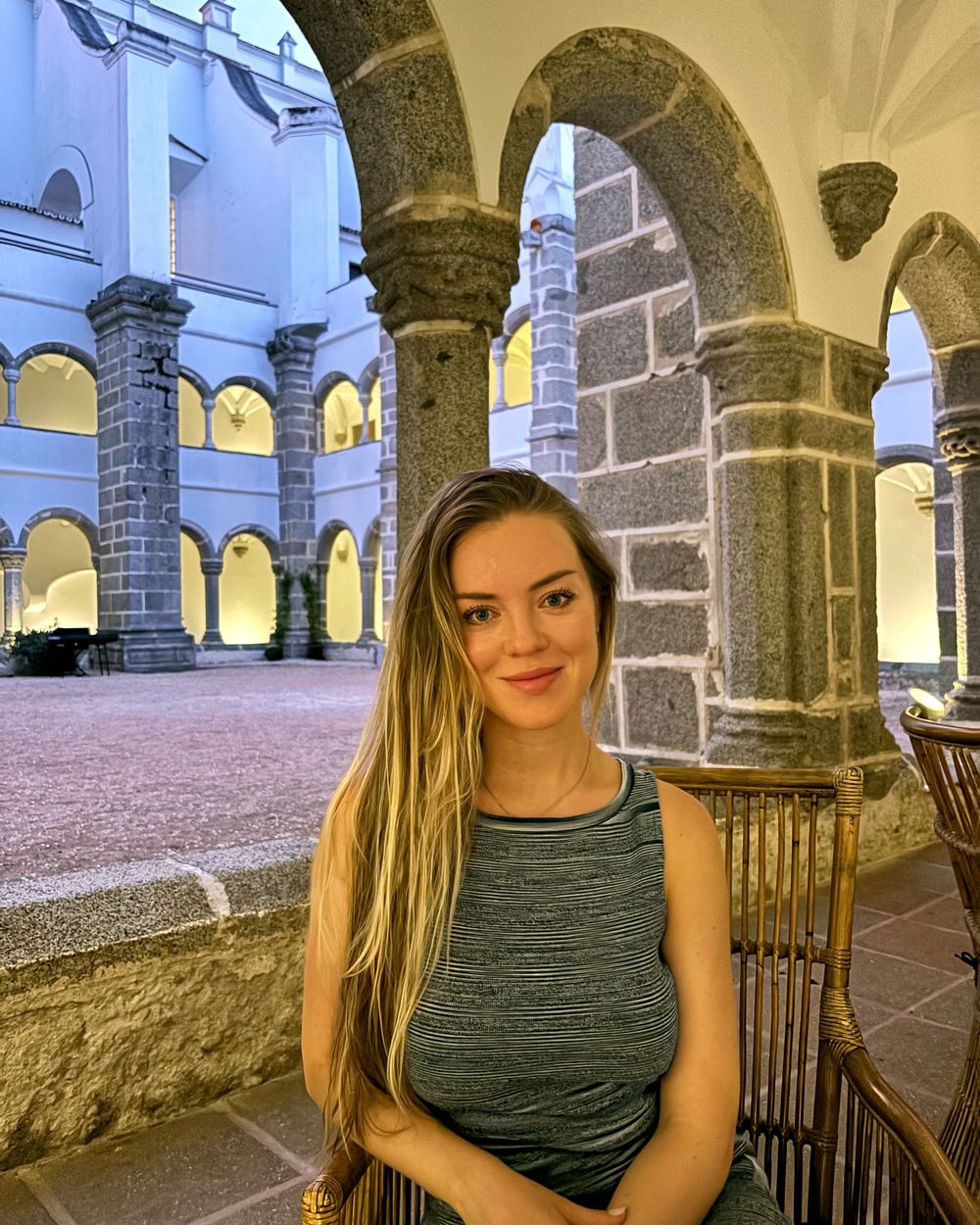 Angelika sitting beneath stone arches in Lisbon